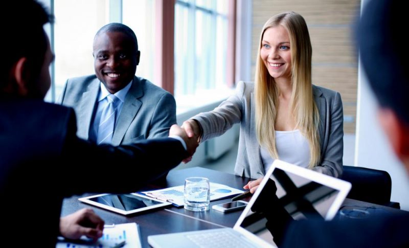 businesspeople shake hands across a table