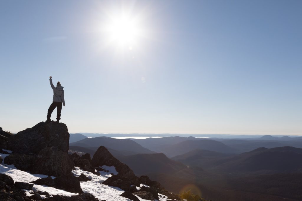 woman holds fist in the air at a mountain summit