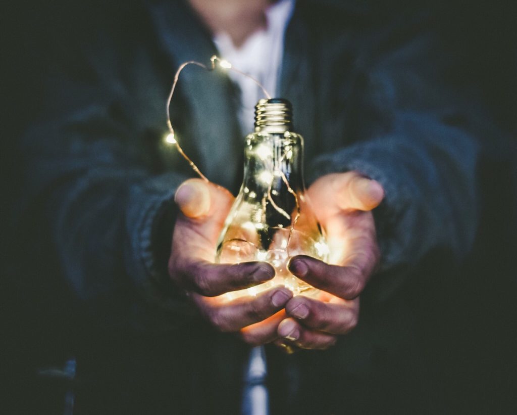 person holds a lightbulb with fairy lights inside