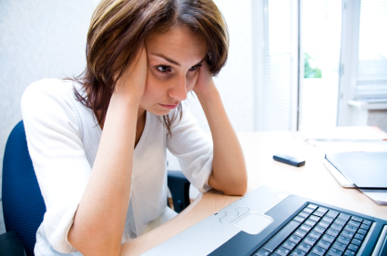 businesswoman holding head in her hands stares at laptop