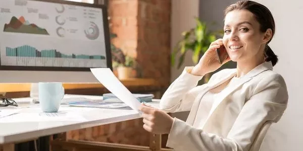 business woman takes phone call sitting at desk