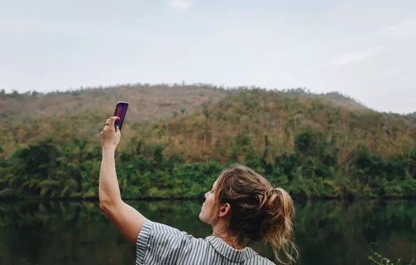 woman alone in nature raising smartphone