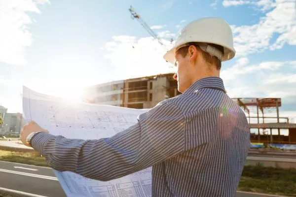 architect in helmet looks at blueprints